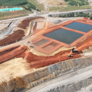 
A imagem exibe áreas de mineração denominadas Malha VII e Malha IV. O terreno apresenta extensas escavações, com grandes crateras e pilhas de terra e rochas resultantes da extração mineral. A paisagem ao redor pode incluir áreas de vegetação impactadas pela atividade mineradora.
