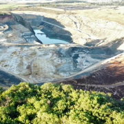 
A imagem da Mina São Vicente Norte, apresenta uma paisagem industrial com vastas áreas de extração. A cena é marcada pela presença de vegetação ao redor, que pode ser afetada pela atividade mineradora. Esta imagem ilustra a relação entre a extração mineral e o meio ambiente
