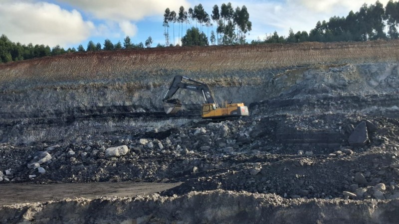 O cenário da imagem é de mineração em Candiota, inclui grandes áreas de exploração, onde o carvão é extraído do solo. Um dos equipamentos utilizados neste processo é um carrinho amarelo, projetado para transportar o carvão das minas até as áreas de processamento.
Esse carrinho amarelo é robusto e possui rodas largas, permitindo a circulação em terrenos irregulares. Ele é normalmente operado por máquinas ou veículos que puxam o carregamento. O design do carrinho é funcional, com uma estrutura aberta que facilita o carregamento e descarregamento do carvão.