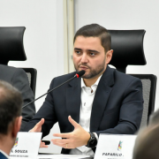 O secretário adjunto Marcelo Camardelli e o vice-governador Gabriel Souza estão sentados lado a lado em uma mesa de reunião. Ambos usam ternos escuros e estão concentrados, observando ou escutando atentamente durante a discussão.