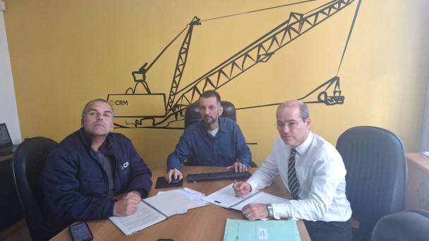 Numa sala ampla de reuni&atilde;o 3 pessoas est&atilde;o sentadas olhando atentas para a tela em reuni&atilde;o remota com a presidente do conselho, Marta. os 3 homens est&atilde;o s&eacute;rios e olhando fixamente para entender o que est&aacute; sendo exposto na reuni&atilde;o.