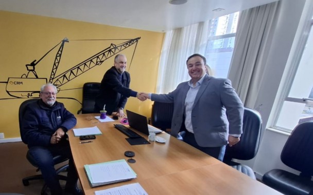 
três pessoas sorrindo para a câmera num aperto de mão entre o presidente Ademir Baretta e o diretor técnico Murilo da Luz empossando como diretor técnico da Companhia.