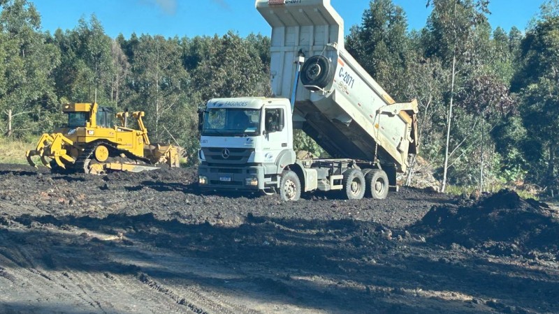 Na imagem aparece 2 m&aacute;quinas trabalhando para o processo de recupera&ccedil;&atilde;o ambiental em Minas do Le&atilde;o, um trator e uma escavadeira. O ch&atilde;o mostra carv&atilde;o sendo retirado a c&eacute;u aberto mostrando uma vegeta&ccedil;&atilde;o ao redor. 