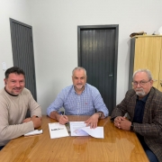A imagem mostra os 3 homens em quest&atilde;o, o presidente da CRM Ademir Baretta no meio dos dois com a caneta assinando a cess&atilde;o de comodato, do seu lado esquerdo, o diretor Jo&atilde;o Batista Alves Rodrigues e do seu lado direito o Vice-Prefeito Daniel Oliboni de Minas do Le&atilde;o. Todos est&atilde;o sorridentes na foto olhando para a c&acirc;mera.